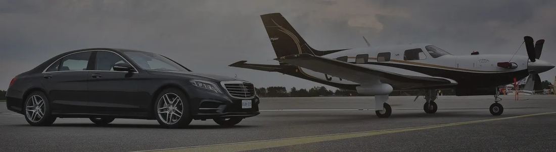 Black executive sedan beside a private jet
